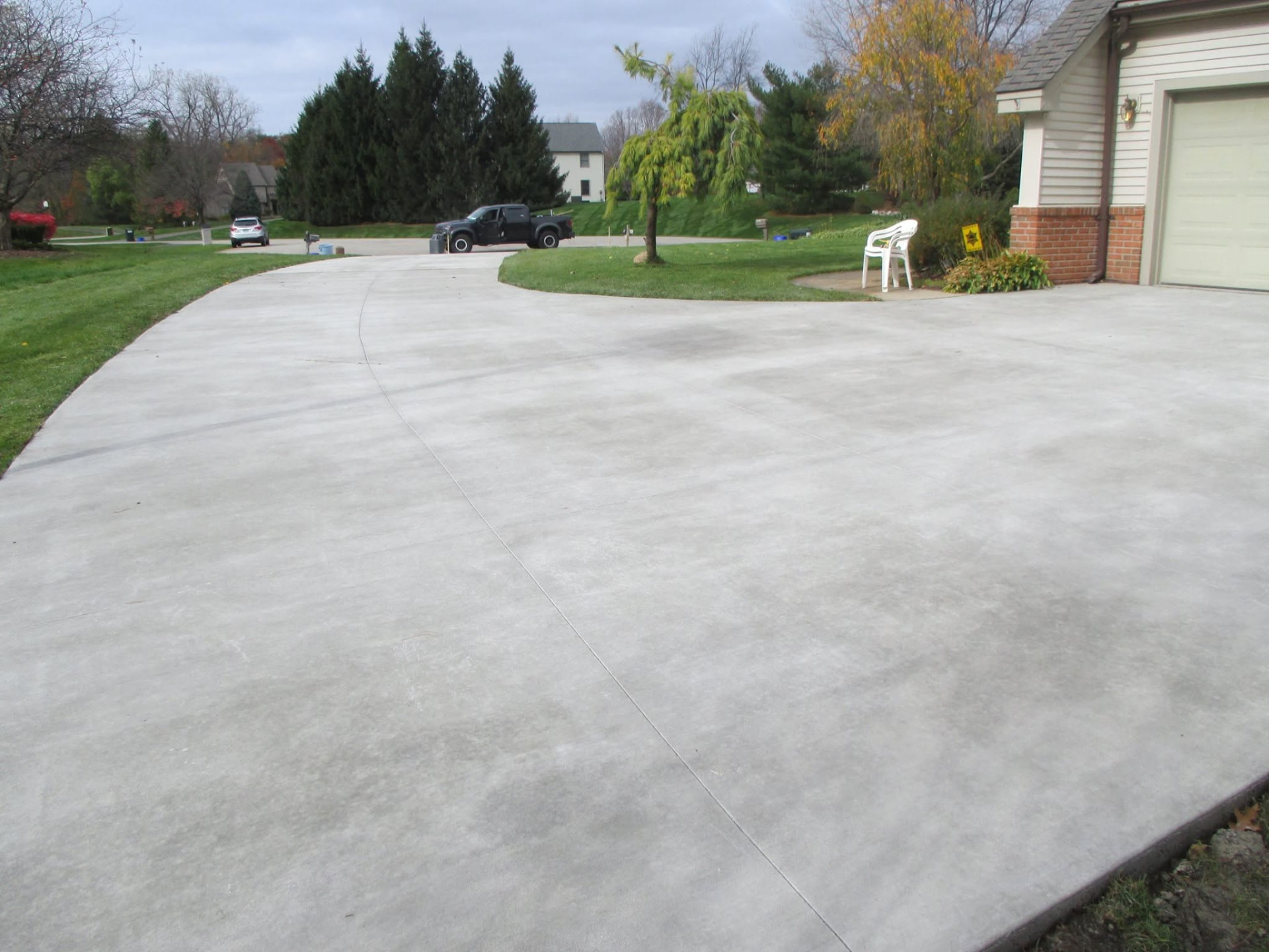 Large curved broom-finish concrete driveway with control joints by Marcucci Concrete Construction in Oakland County, Michigan