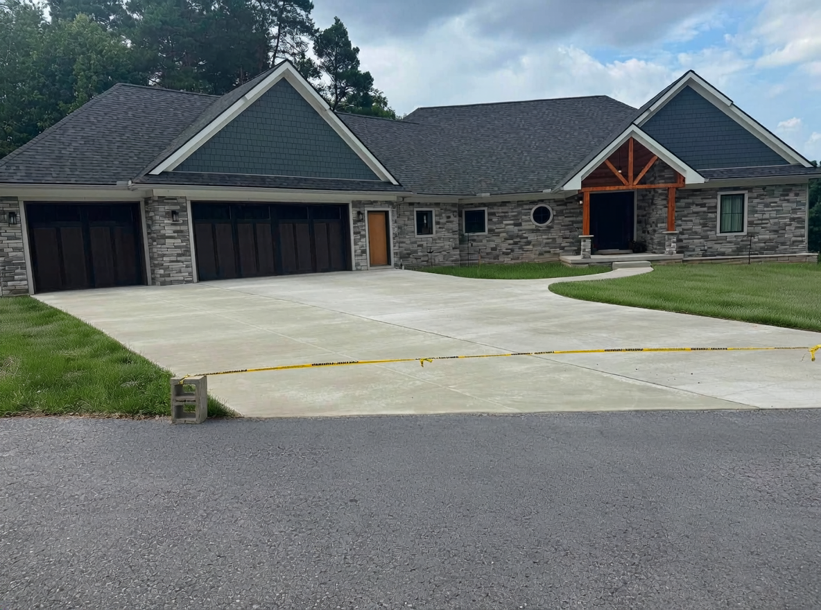 New concrete driveway and three-car garage apron at a stone ranch home in Oakland County, MI by Marcucci Concrete