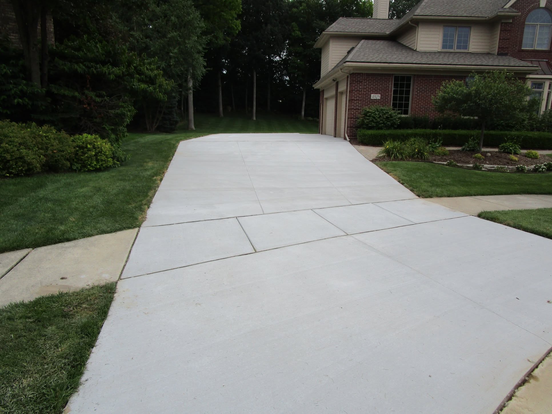 Finished concrete driveway replacement by Marcucci Concrete Construction at a brick home in West Bloomfield, Michigan