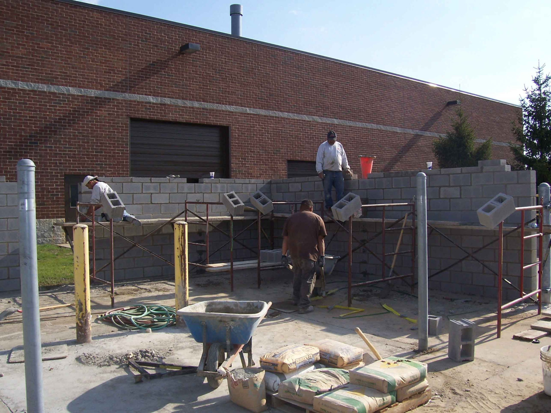 Masons laying a commercial concrete block wall on scaffolding for Marcucci Concrete Construction in Oakland County, Michigan
