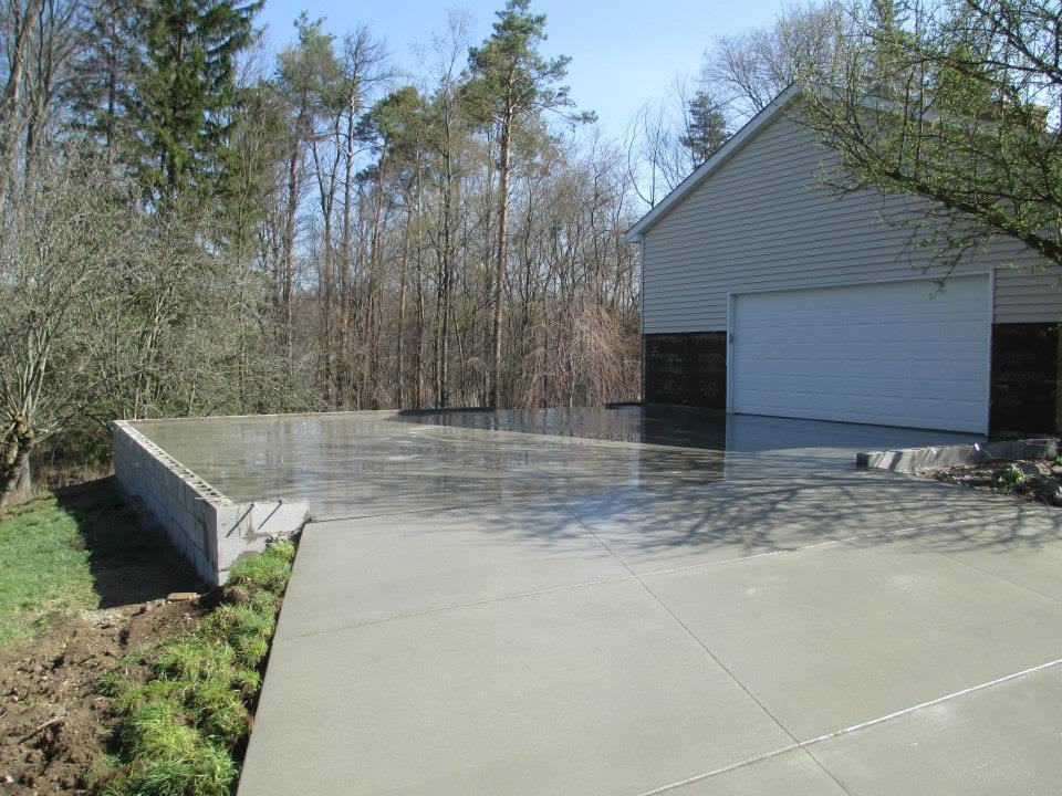 Concrete driveway with a block retaining wall and attached garage slab. Marcucci Concrete Construction in Oakland County, Michigan.