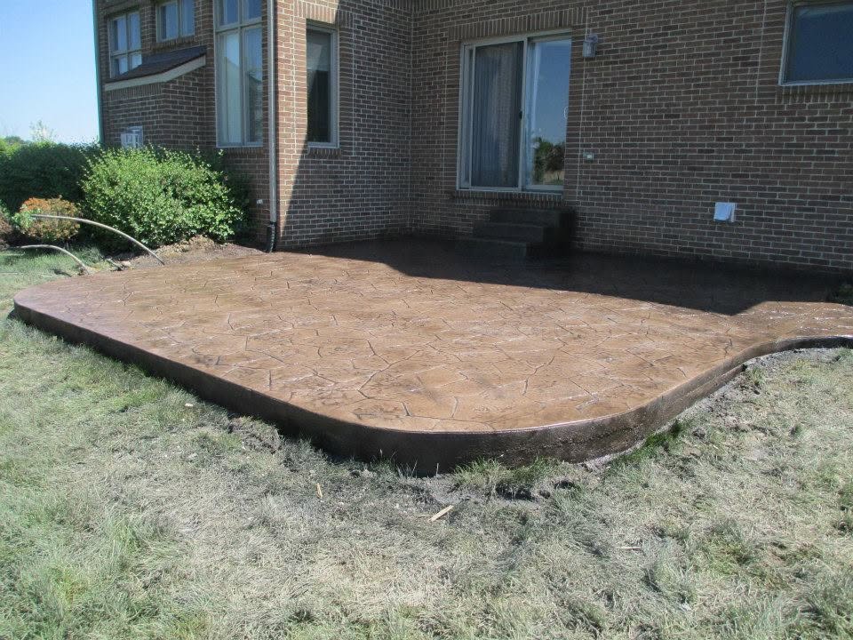 Brown stamped concrete patio with an irregular stone pattern and curved edge by Marcucci Concrete Construction in Oakland County, Michigan