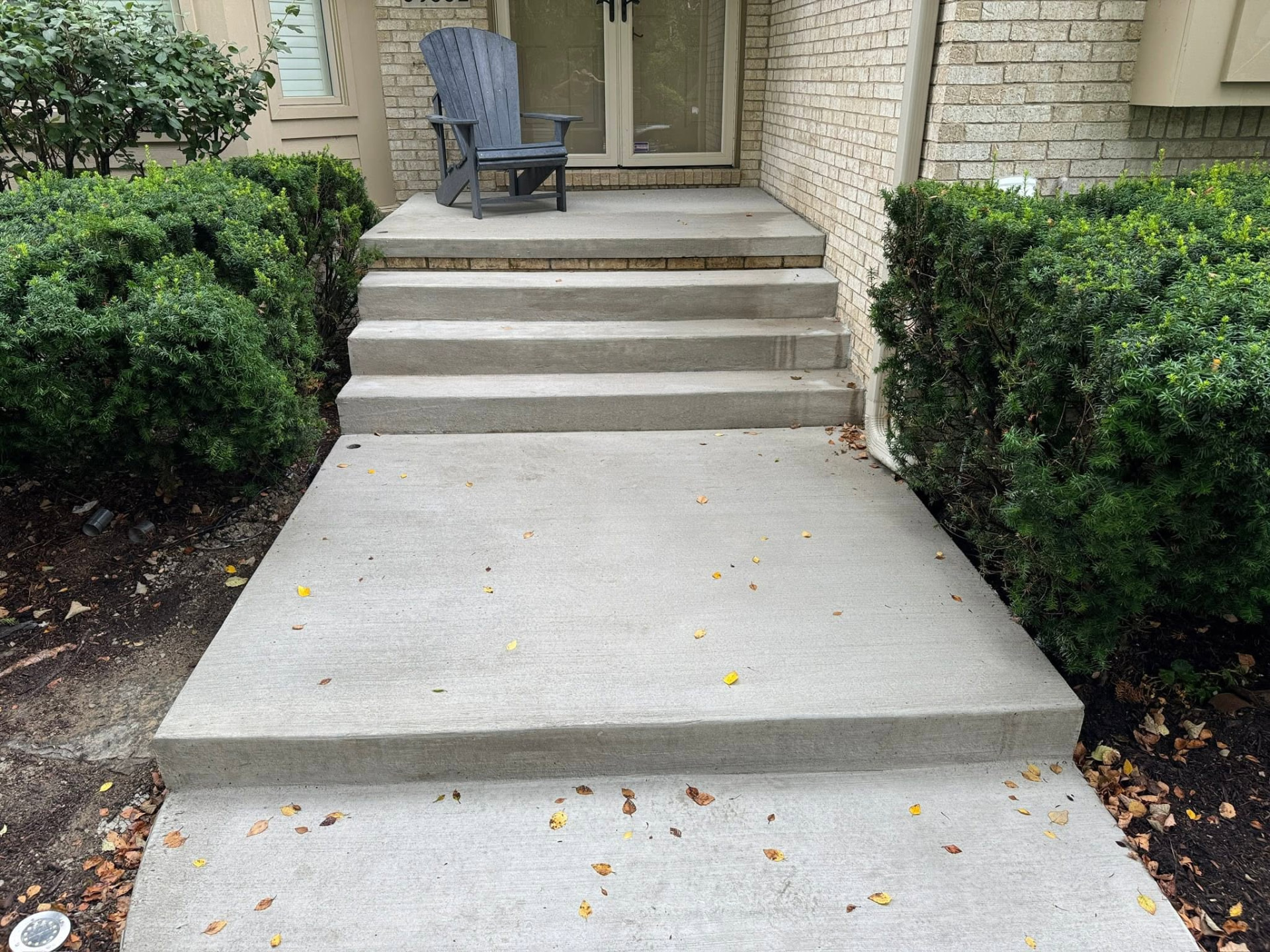 New concrete porch landing, wide entry steps and connecting front walk at a residential entrance. Marcucci Concrete Construction in Oakland County, Michigan.