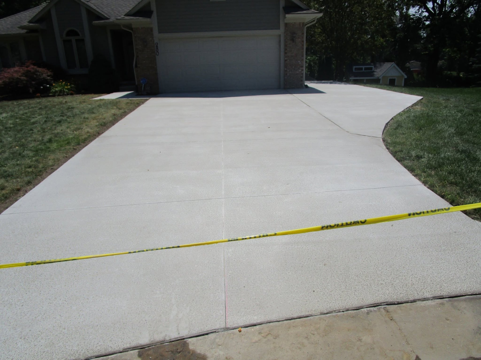 Wide broom-finish concrete driveway with a side parking extension by Marcucci Concrete Construction in Oakland County, Michigan
