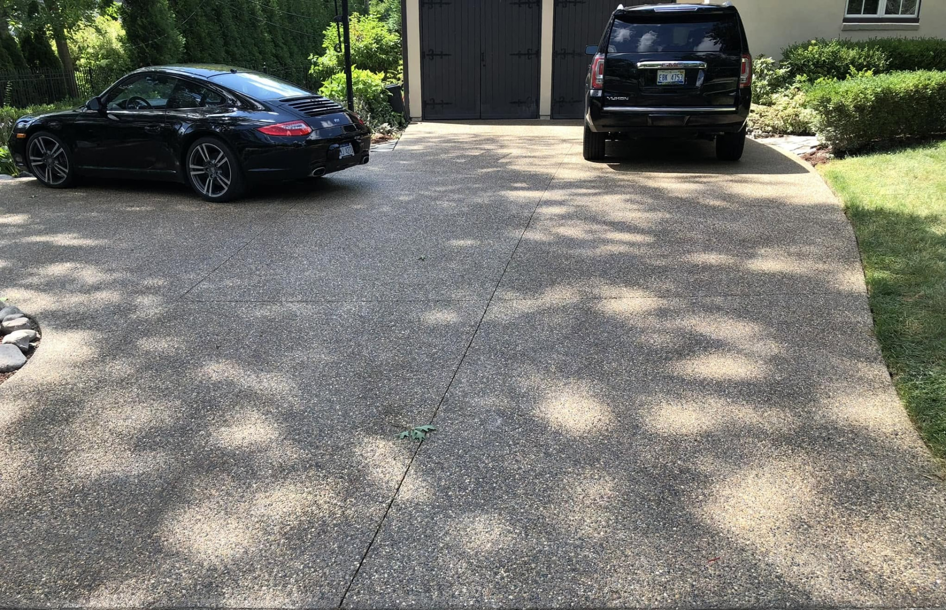 Exposed aggregate concrete driveway with curved apron and saw-cut control joints by Marcucci Concrete in Oakland County, Michigan
