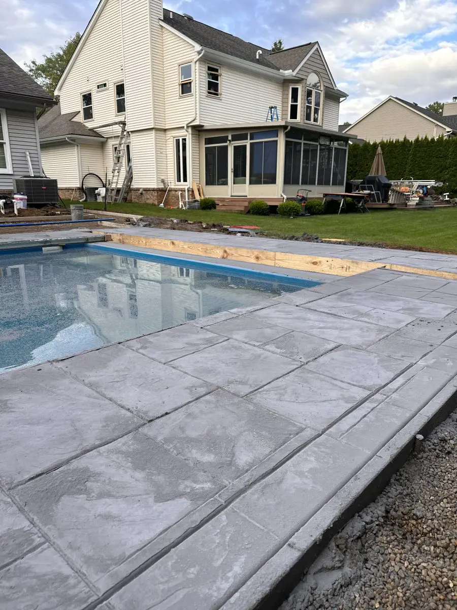 New stamped concrete pool deck with forms still in place and gravel base at the edge, by Marcucci Concrete Construction in Oakland County, Michigan
