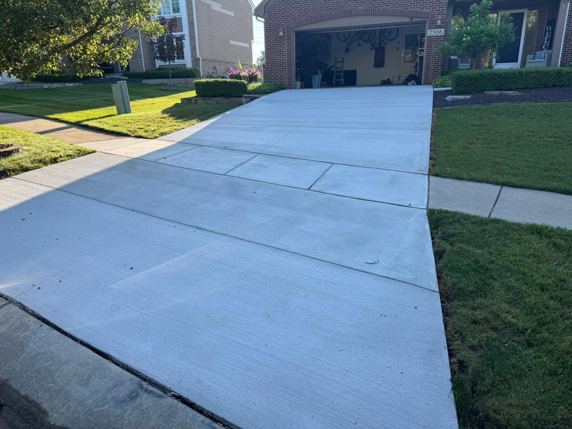 Finished concrete driveway with clean control joints leading to a two-car garage at a brick home. Marcucci Concrete Construction in Oakland County, Michigan.