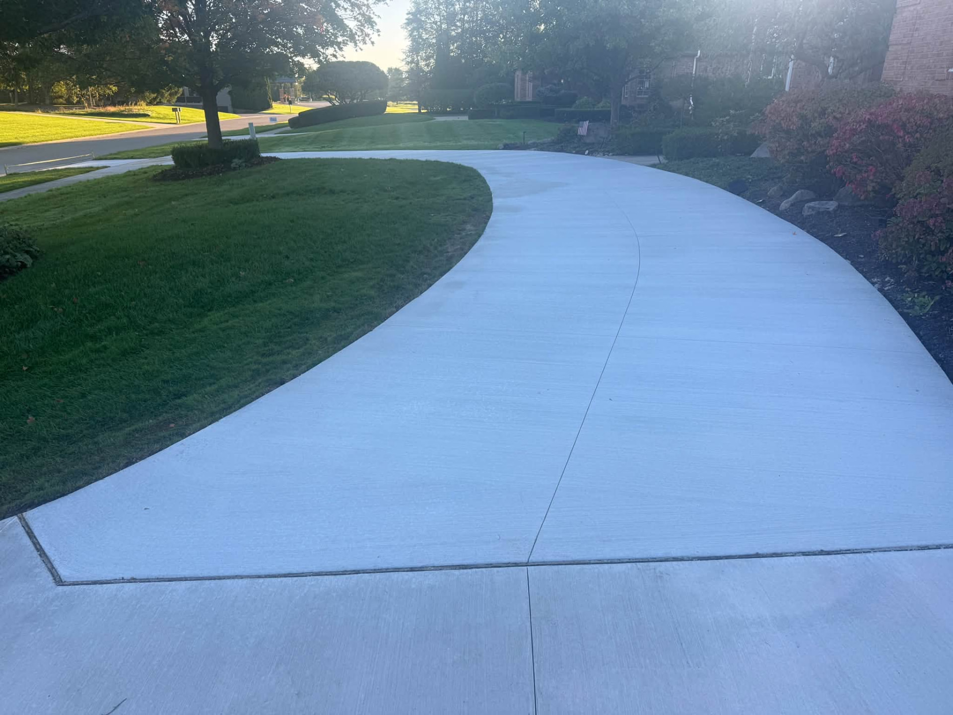Wide curved broom-finish concrete driveway installed by Marcucci Concrete Construction in Oakland County, Michigan