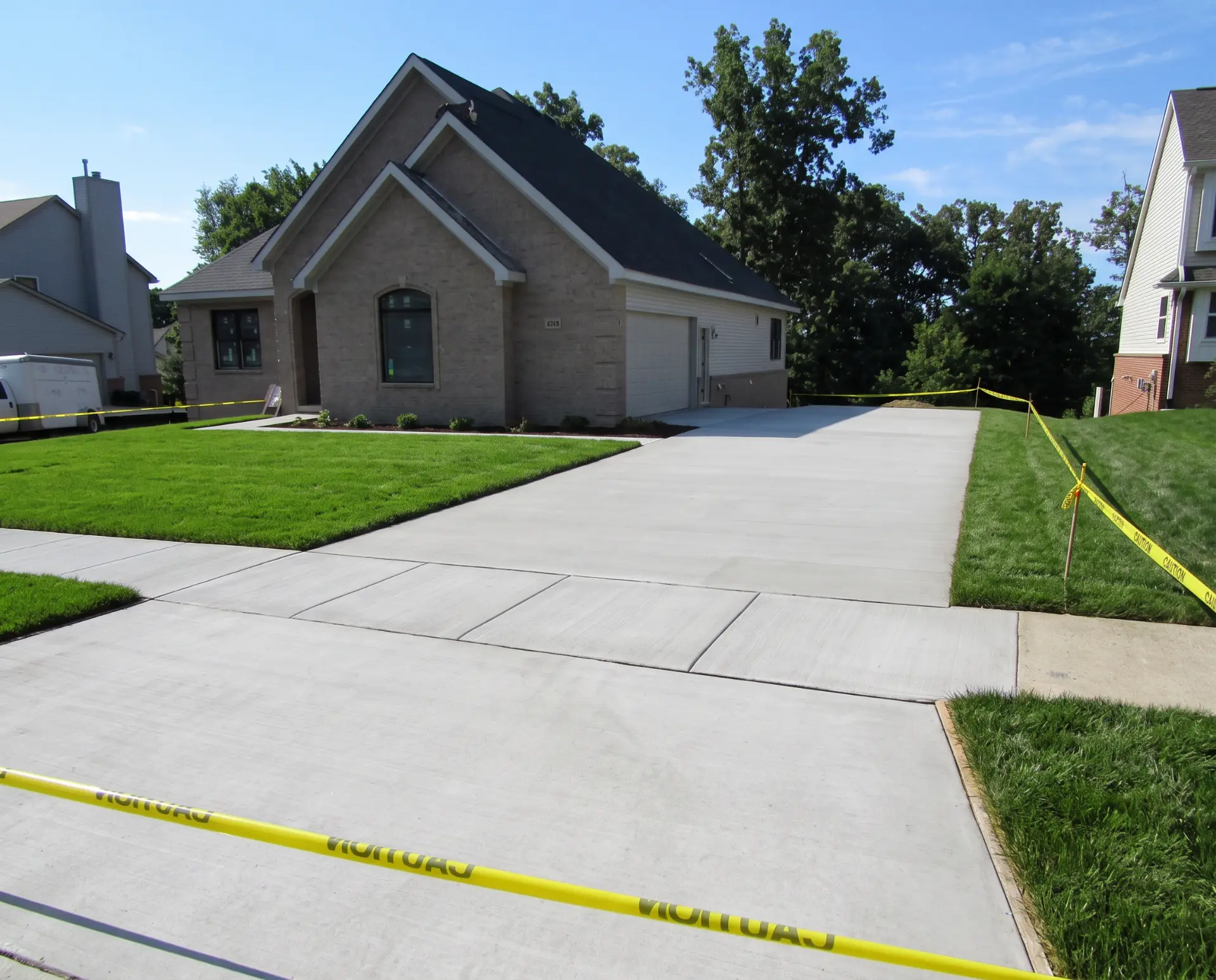 New concrete driveway and connecting sidewalk for a new construction home, poured with a broom finish and saw-cut control joints by Marcucci concrete driveway contractors in Oakland County, MI