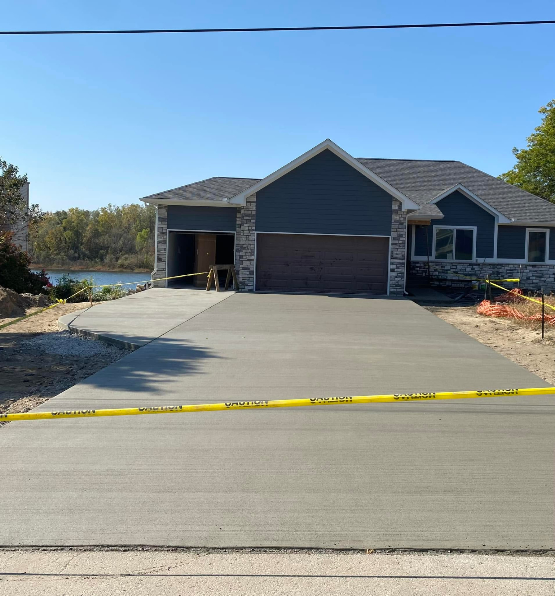 New broom-finish concrete driveway and garage apron at a lakefront home by Marcucci Concrete Construction in Oakland County, Michigan