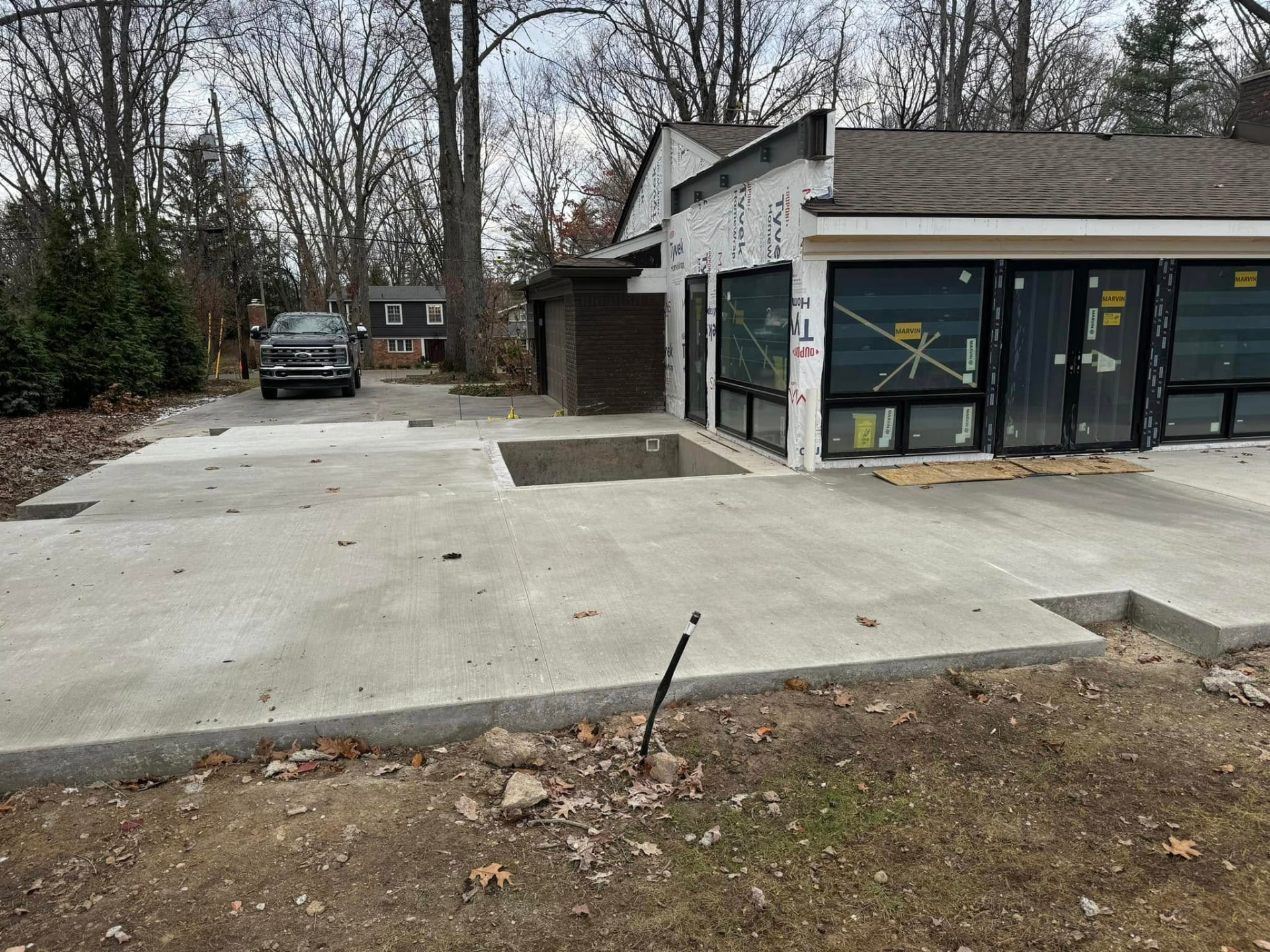 Broom-finish concrete patio slab with formed edge beside a driveway by Marcucci Concrete Construction in Oakland County, Michigan