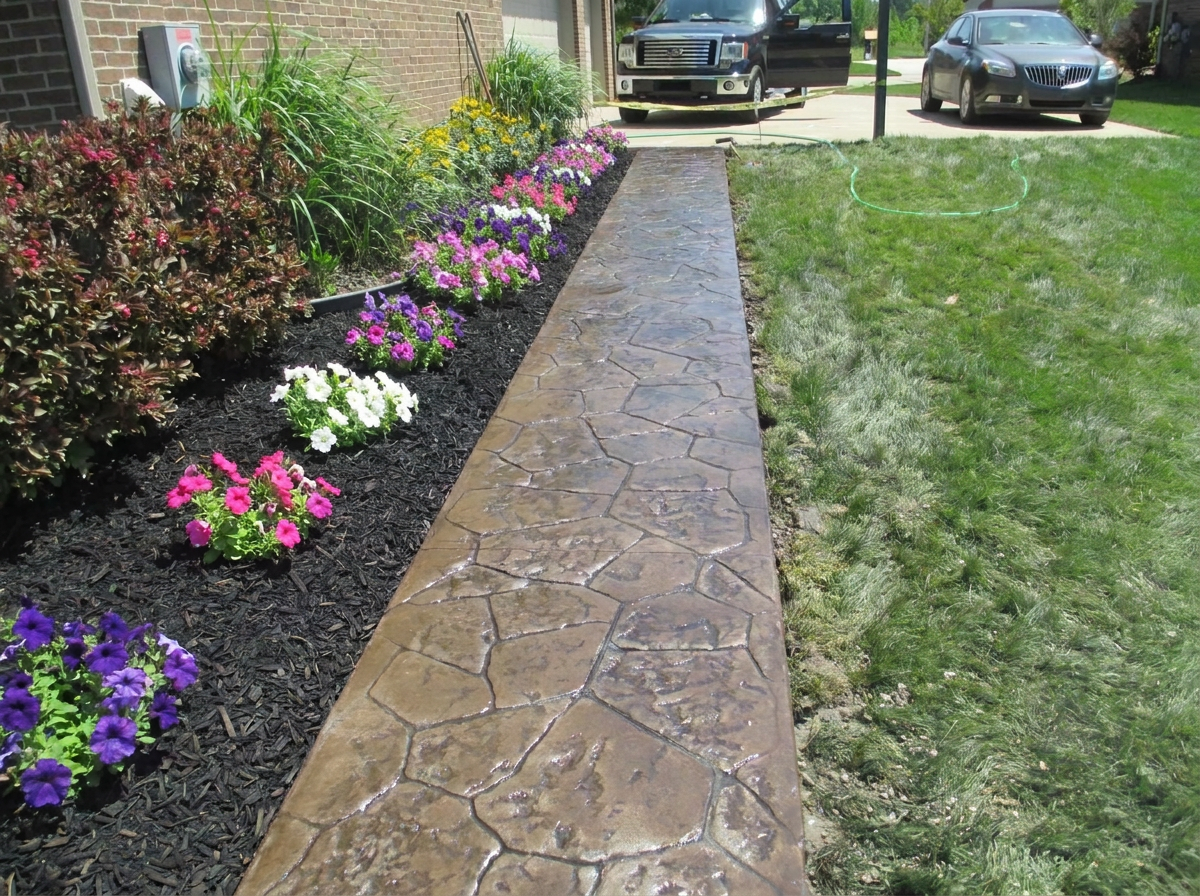 Stamped and colored concrete walkway beside landscaped flower beds by Marcucci Concrete Construction in Oakland County, Michigan