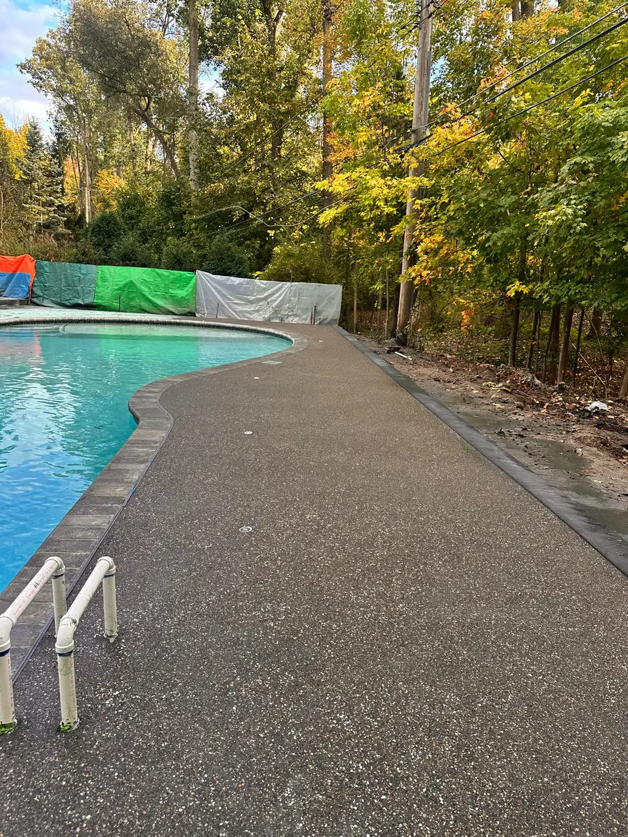 Exposed aggregate concrete pool deck replaced around an existing swimming pool by Marcucci Concrete Construction in Oakland County, Michigan