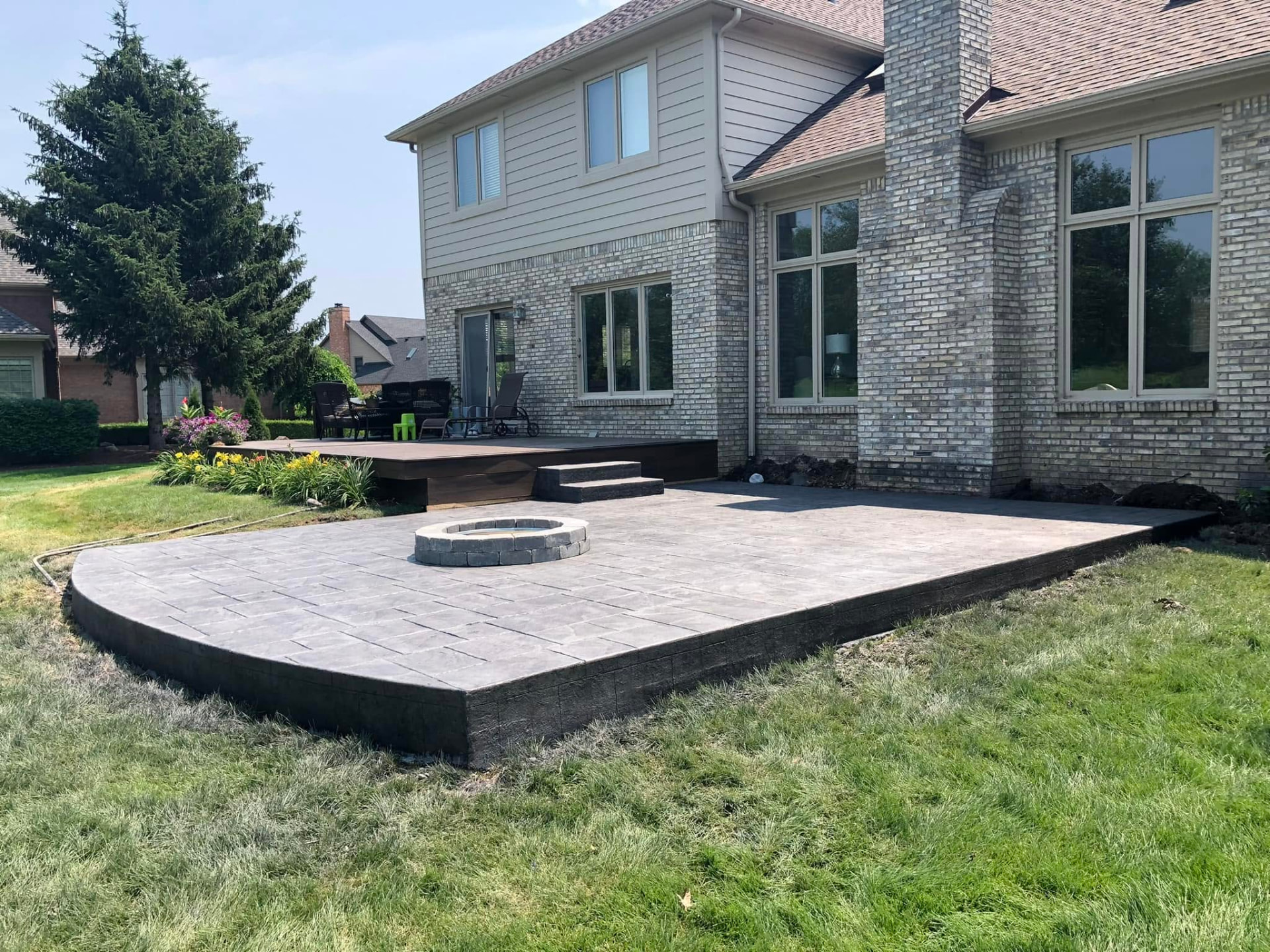 Raised stone-pattern stamped concrete patio with built-in stone fire pit by Marcucci Concrete Construction in Oakland County, Michigan
