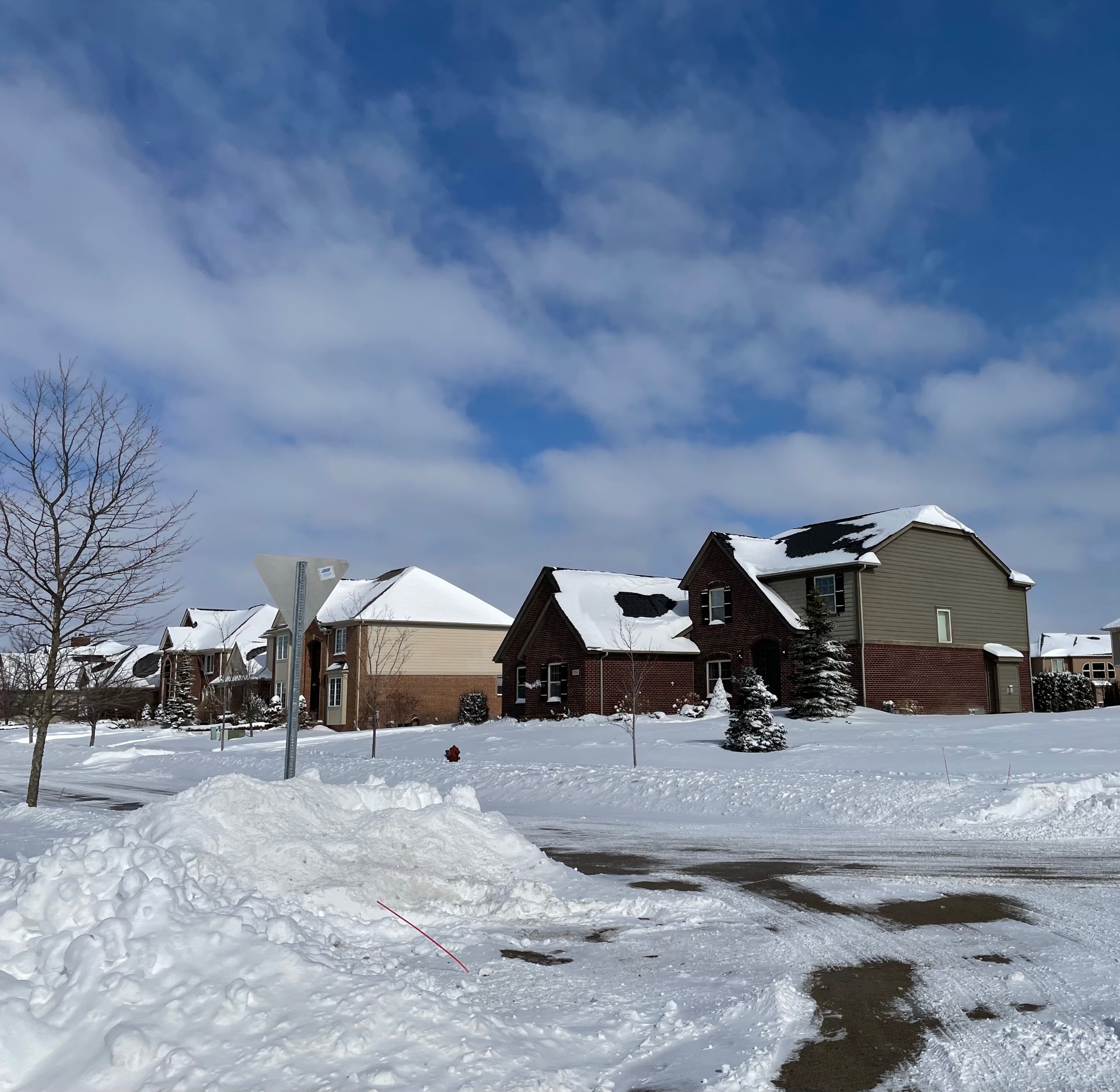 Plowed subdivision road with snow stakes marking the turn, under an HOA snow contract. Marcucci Concrete Construction in Oakland County, Michigan.