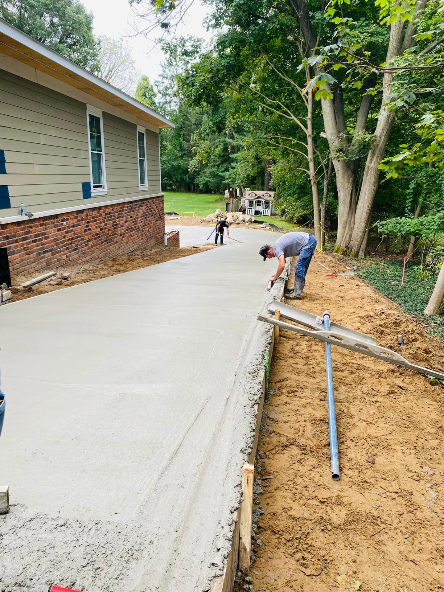 Marcucci crew member hand-tooling the edge of a freshly placed residential concrete driveway along the forms. Marcucci Concrete Construction in Oakland County, Michigan.