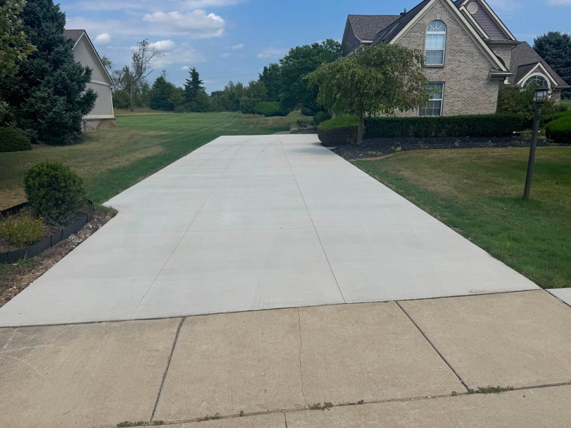 Finished broom-finish concrete driveway replacement with control joints in Oakland County, Michigan