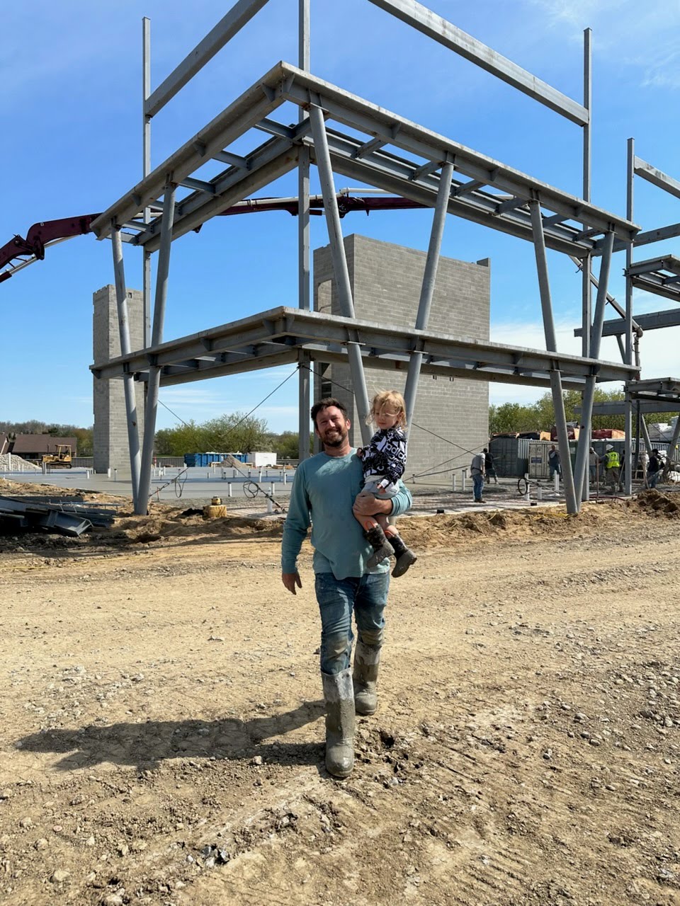 Tony Marcucci of Marcucci Concrete walking a commercial concrete construction site with steel framing and a concrete pump in Michigan