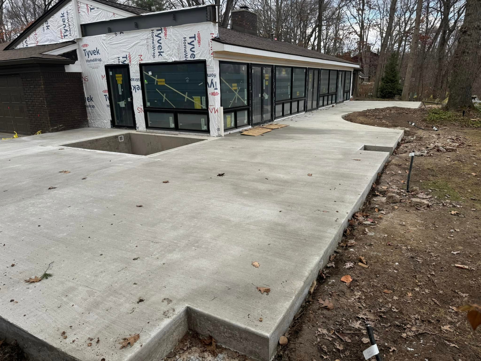 Expansive broom-finish concrete patio wrapping a renovated home by Marcucci Concrete Construction in Oakland County, Michigan