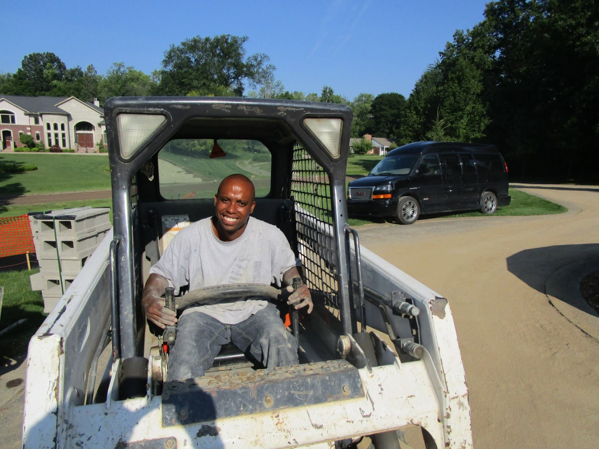 Marcucci Concrete Construction crew member operating a skid steer for driveway grading in Oakland County, Michigan